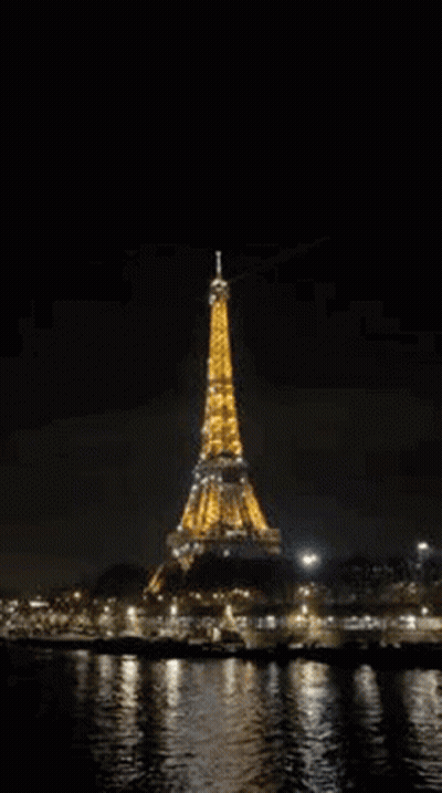 The Eiffel Tower Is Lit Up At Night In Paris , France . GIF