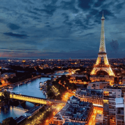 The Eiffel Tower Is Lit Up At Night With A Blue Sky In The Background GIF