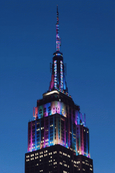 The Empire State Building Is Lit Up With Colorful Lights At Night GIF