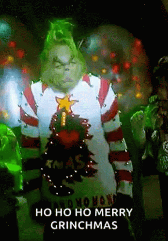 The Grinch Is Wearing A Sweater With A Christmas Tree On It And Is Standing In Front Of A Group Of People . GIF