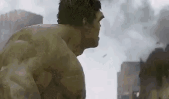 The Hulk Is Standing In Front Of A City In A Movie Scene . GIF
