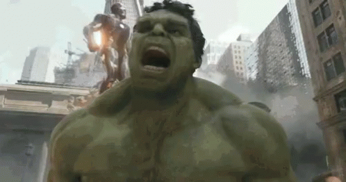 The Hulk Is Standing In Front Of A City With His Mouth Open GIF
