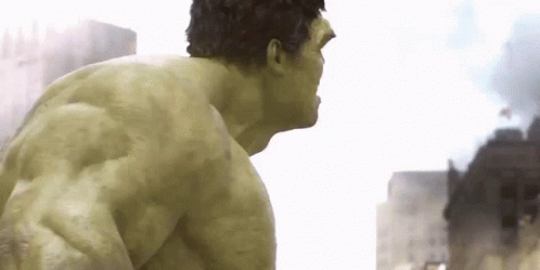 The Hulk Is Standing In Front Of A City With Smoke Coming Out Of It GIF