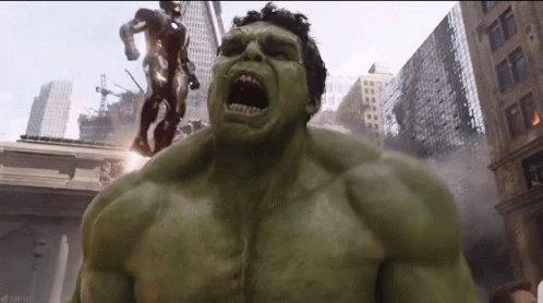 The Hulk Is Standing In Front Of A Statue Of Iron Man . GIF