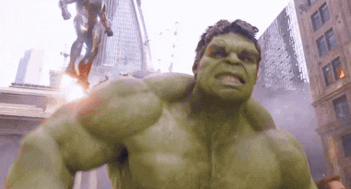 The Hulk Is Standing In The Middle Of A City With A Statue In The Background GIF