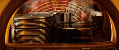 The Inside Of A Jukebox With A Stack Of Records On The Bottom Shelf GIF