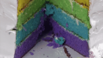 The Inside Of A Rainbow Cake With A Slice Taken Out Of It GIF