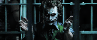 The Joker Is Behind Bars In A Dark Room GIF