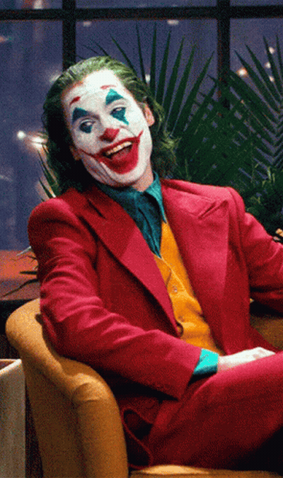 The Joker Is Sitting In A Chair And Smiling GIF