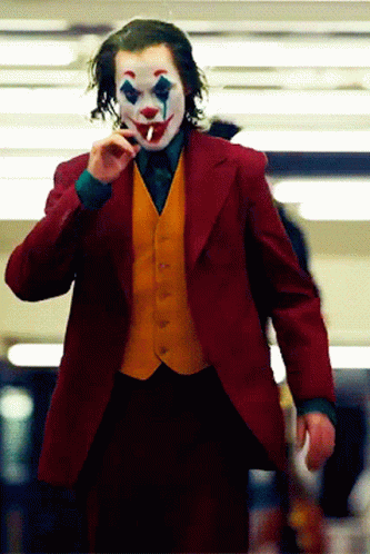 The Joker Is Smoking A Cigarette While Wearing A Red Jacket And Yellow Vest GIF