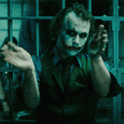 The Joker Is Standing In A Prison Cell With His Hands Up GIF