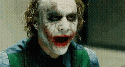 The Joker Is Wearing A Green Vest And Making A Funny Face . GIF