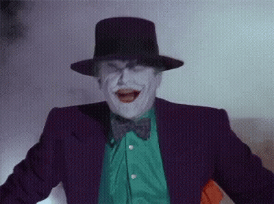 The Joker Is Wearing A Purple Suit And Top Hat And Making A Funny Face . GIF