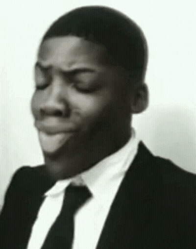The Man Is Wearing A Suit And Tie And Making A Funny Face . GIF