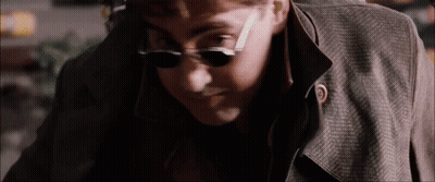 The Man Is Wearing Sunglasses And A Trench Coat . GIF