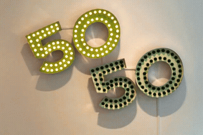 The Numbers 50 And 50 Are Displayed On A White Wall GIF