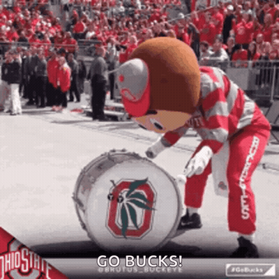 The Ohio State Mascot Is Playing A Drum In Front Of A Crowd . GIF