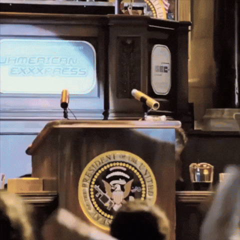 The President Of The United States Stands At A Podium In Front Of An American Express Television GIF