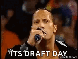 The Rock Is Holding A Microphone In Front Of A Crowd And Says `` It 'S Draft Day '' . GIF