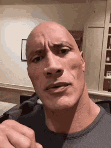 The Rock Is Making A Funny Face And Pointing At The Camera While Wearing A Gray Shirt . GIF
