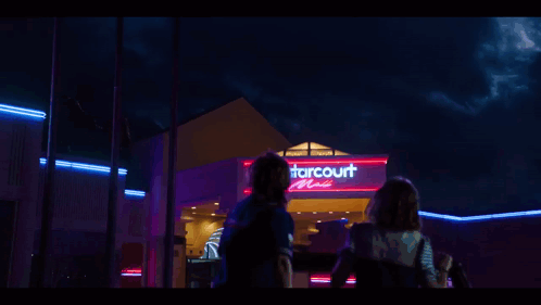 The Starcourt Mall Is Lit Up At Night With Neon Lights GIF