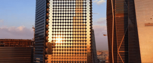 The Sun Is Reflected In A Building With A Checkered Pattern GIF