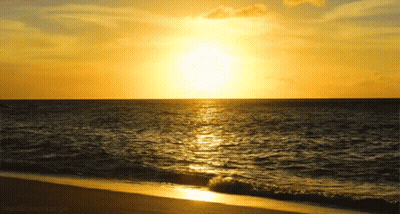 The Sun Is Setting Over A Body Of Water And A Beach Is Visible GIF
