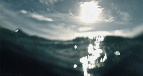 Sun Shining Through Clouds Over Ocean GIF