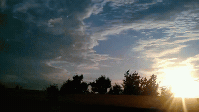 The Sun Is Shining Through The Clouds Over A Fence GIF