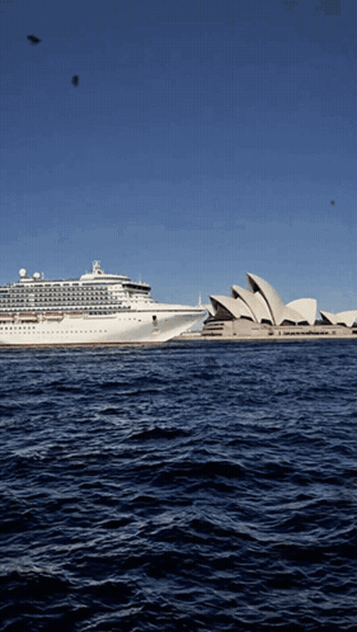 The Sydney Opera House Is Visible In The Distance With A Cruise Ship In The Foreground GIF