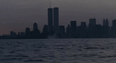 The Twin Towers Are Visible In The Distance Behind A Boat GIF