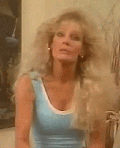 The Woman Is Wearing A Blue Tank Top And Has Very Long Blonde Hair . GIF