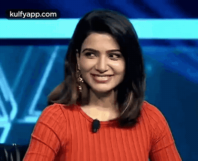 The Woman Is Wearing A Red Sweater And Smiling . GIF