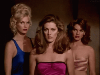 Three Beautiful Women Are Standing Next To Each Other In A Dark Room . GIF