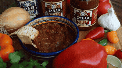 Three Bottles Of 213 Salsa Are On A Table With Vegetables GIF