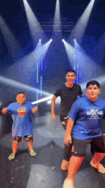Three Boys Are Dancing On A Stage In Front Of A Stage With Lights . GIF