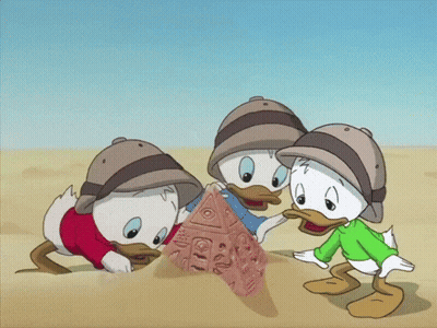 Three Cartoon Ducks Playing In Sand One In Green Shirt GIF