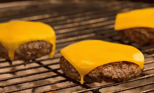 Three Cheeseburgers Cooking On Grill GIF