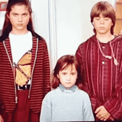 Three Children Are Standing Next To Each Other In A Room . One Of The Children Is Wearing A Butterfly Shirt . GIF