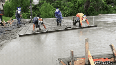 Three Construction Workers Are Working On A Concrete Floor GIF