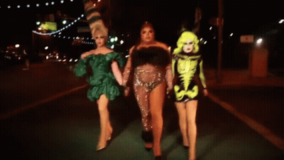 Three Drag Queens Walking At Night Holding Hands GIF
