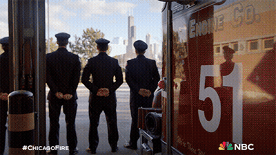 Three Firefighters Stand In Front Of A Chicago Fire Truck GIF