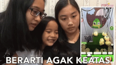 Three Girls Are Looking At A Screen With The Words Berarti Agak Keatas On The Bottom GIF