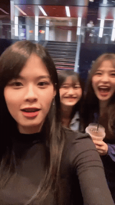 Three Girls Are Posing For A Picture And One Is Holding A Cup Of Coffee GIF