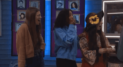 Three Girls Are Standing In Front Of A Wall With Pictures Of People GIF