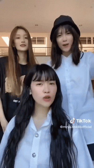 Three Girls Are Standing Next To Each Other In A Room . One Of The Girls Is Wearing A Hat . GIF