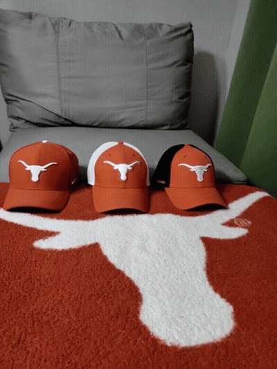 Three Hats With Longhorns On Them Are On A Couch GIF
