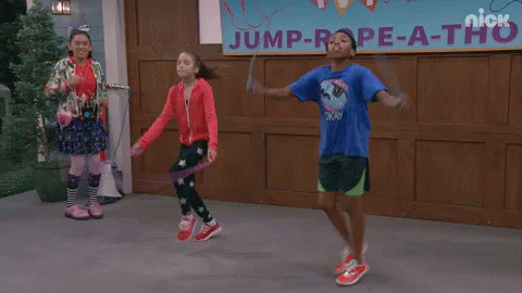 Three Kids Jump Rope In Front Of A Sign That Says Jump Rope-A-Thon GIF