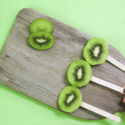 Three Kiwi Popsicle Slices On Wooden Board GIF