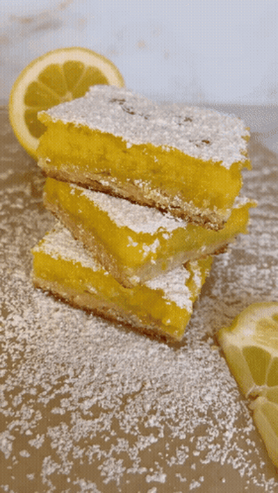 Three Lemon Bars Stacked With Powdered Sugar GIF